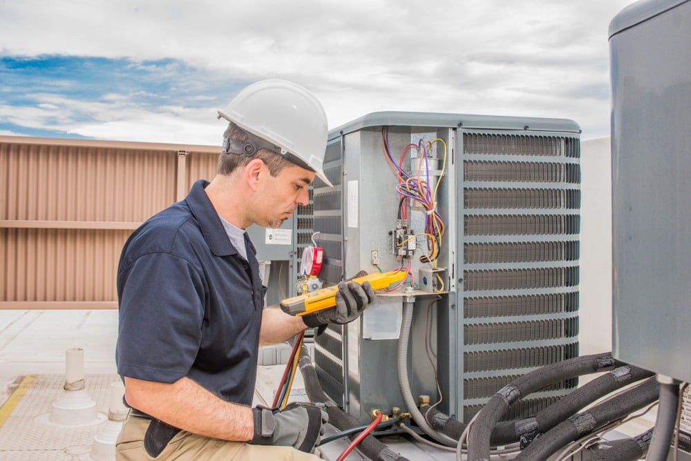 A professional from Howard Air repairs an outdoor AC unit and reviews AC maintenance tips
